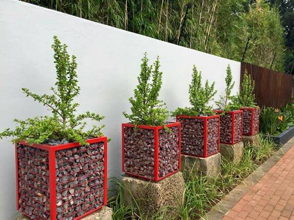 Red color gabion planters with angel steel beside of the garden wall.