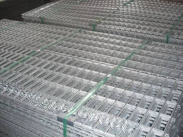 Several bundles of welded wire mesh panels and spiral binders on the ground.